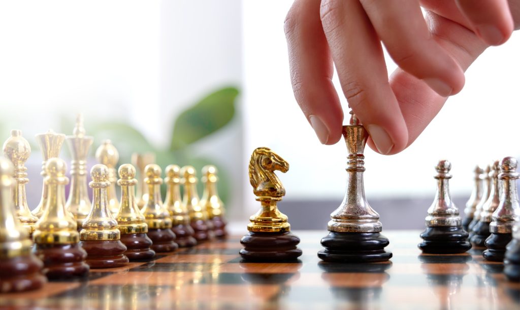 Wide cropped image of a human hand moving King chess piece at table
